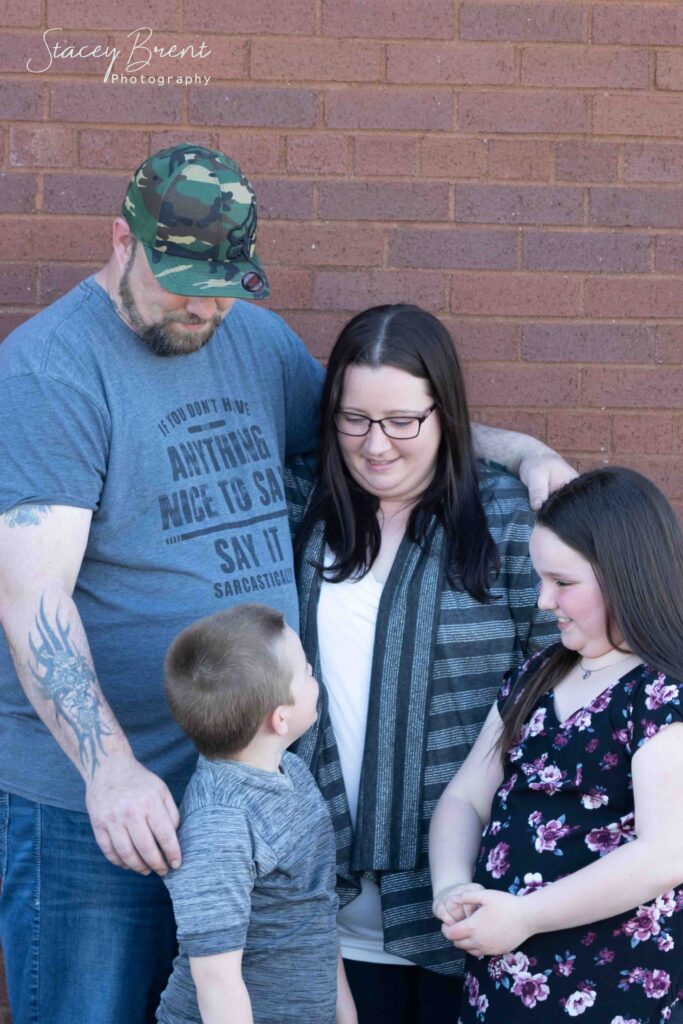 Family of 4 against a Brick wall outdoors. Stacey Brent Photography, Central Newfoundland.